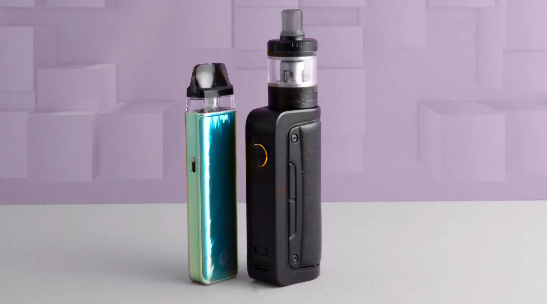 Sub-ohm and pod vape kit photographed together on a purple block background